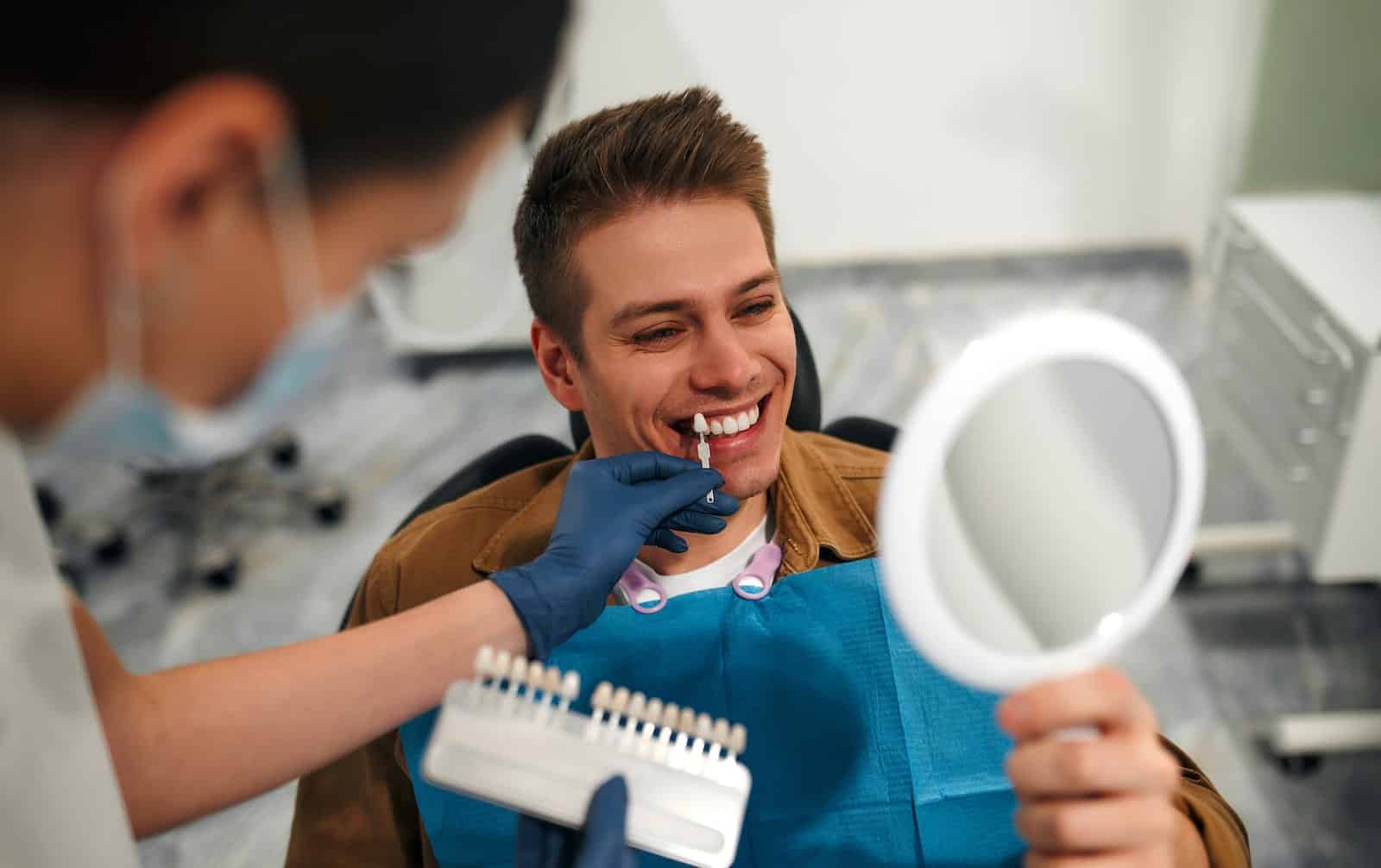 Dental hygienist matching veneers to colour of man's natural teeth