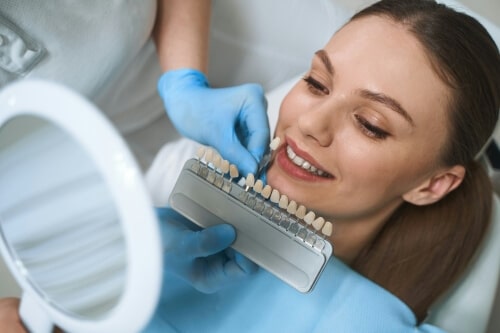 Dentist matching veneers to woman's teeth