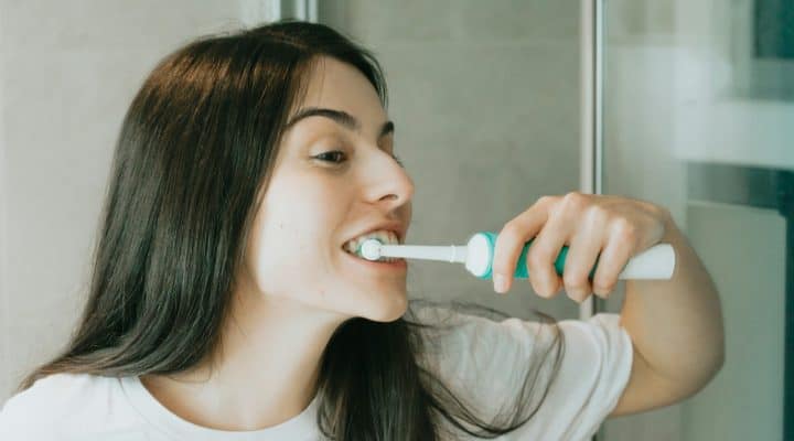 Woman brushing her teeth before breakfast