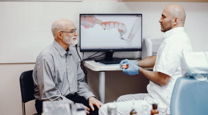 dentist consulting with patient all on 4 vs custom dental implants vs dentures