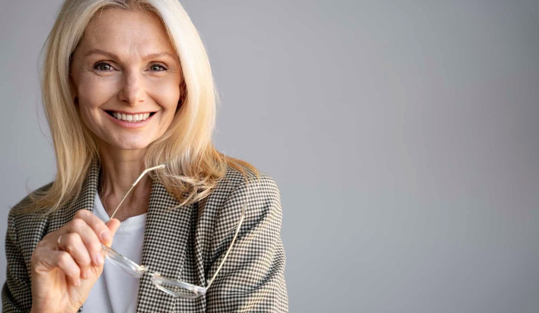 middle aged woman smiling holding glasses